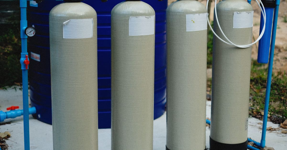 A reverse-osmosis membrane cartridge cut open beside a stack of filter housings.